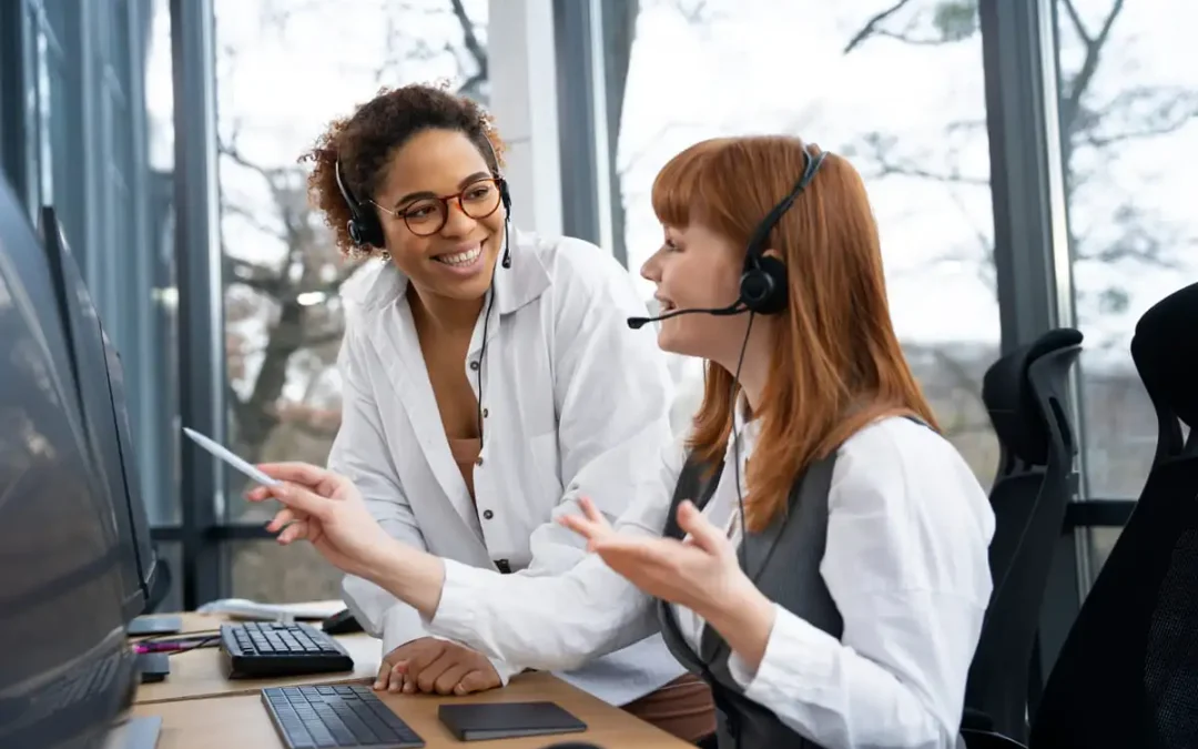 Atendentes de telemarketing sorrindo durante atendimento ao cliente em escritório.